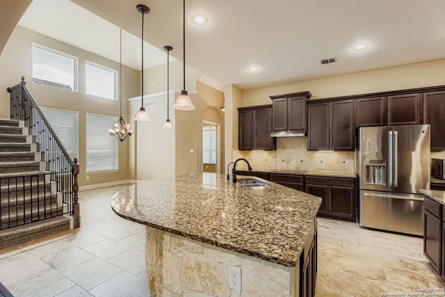 a kitchen with kitchen island granite countertop a sink a counter space appliances and cabinets