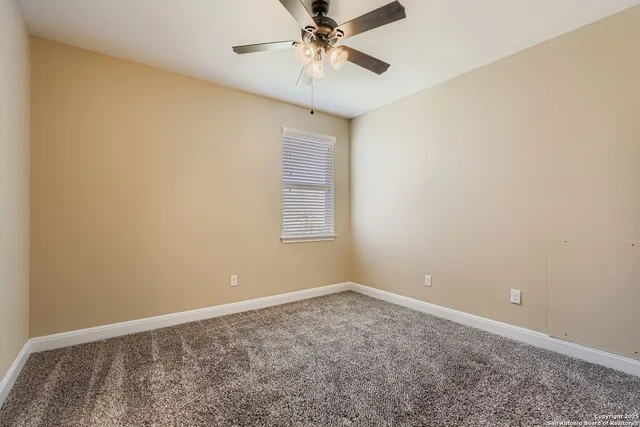 an empty room with a window and a ceiling fan