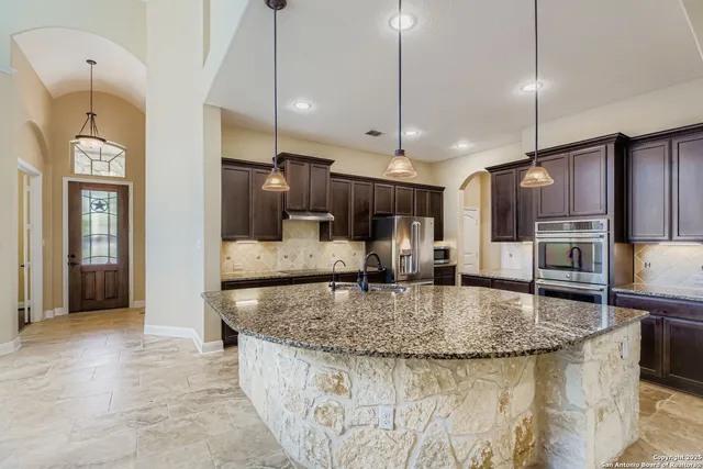 a kitchen with stainless steel appliances granite countertop a sink a oven and a refrigerator