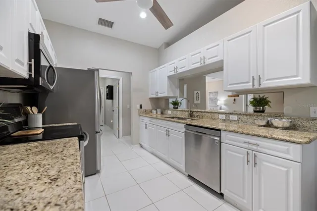 a kitchen with kitchen island granite countertop a sink white cabinets and chairs