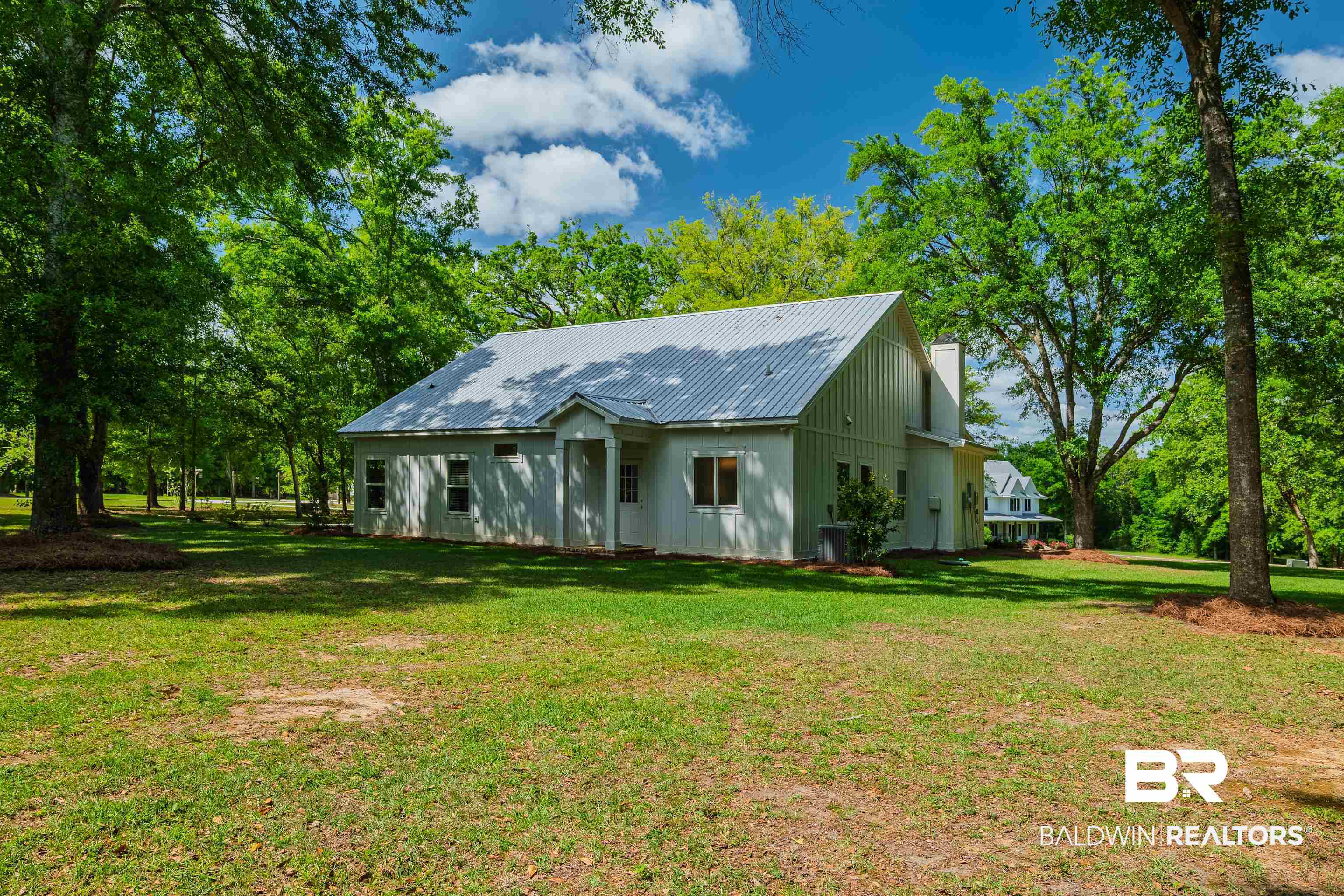 19121 Boothe Road Fairhope, AL 36532 - Photo 29 of 41 View of front of house featuring a metal roof, a front yard, a chimney, and view of wooded area