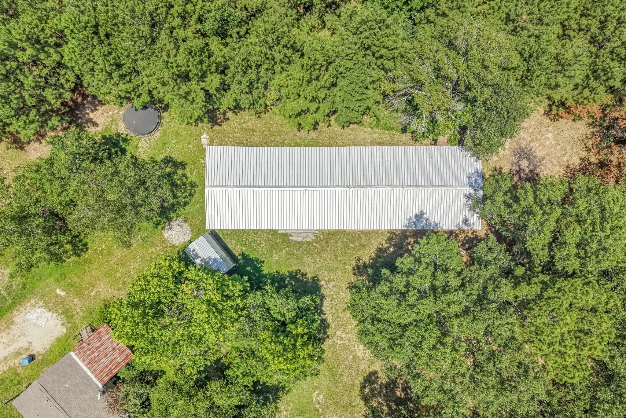 25979 Shade Tree Lane Splendora, TX 77372 - Photo 16 of 22 A standout feature of the property, the impressive 30' x 100' metal building offers exceptional versatility - ideal for storage, projects, equipment, recreational vehicles, or endless possibilities.