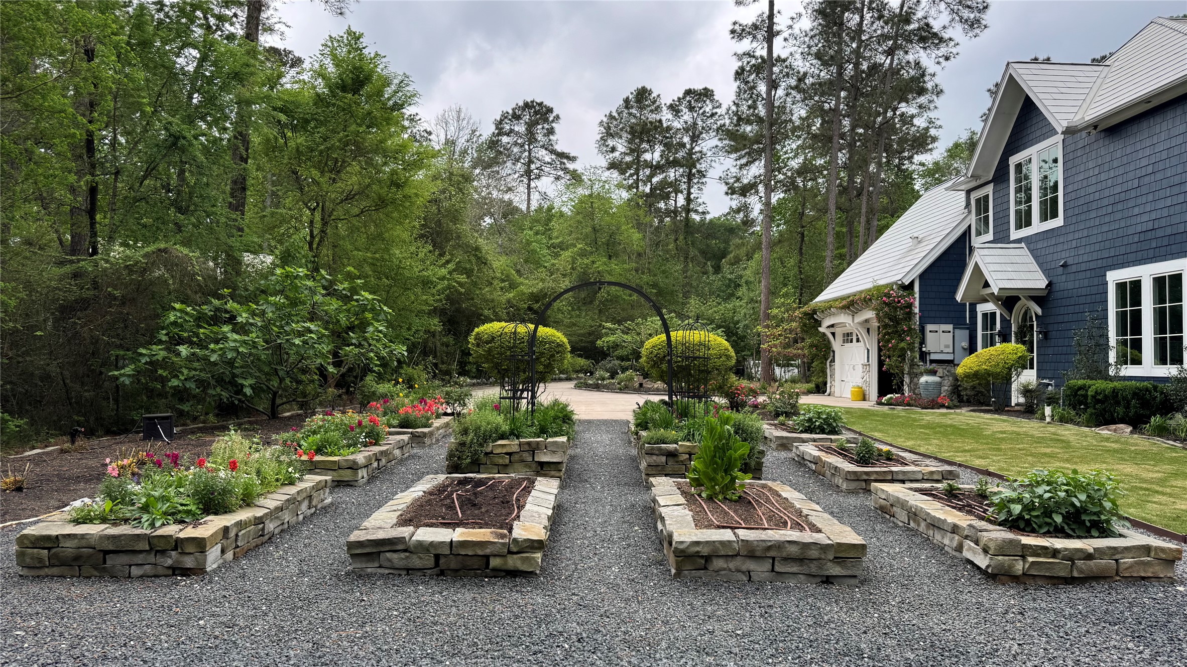 10 Riata Drive Magnolia, TX 77354 - Photo 11 of 48 Professional landscaping inclusive of apple, peach, fig, + pecan trees, Zoysia grass surrounding home, and a large field with Celebration Bermuda grass. Additionally find low-voltage landscape lighting throughout property, French drains, dry river beds, and 32-zone irrigation system 12-bed garden with drip irrigation and black star gravel walking paths.