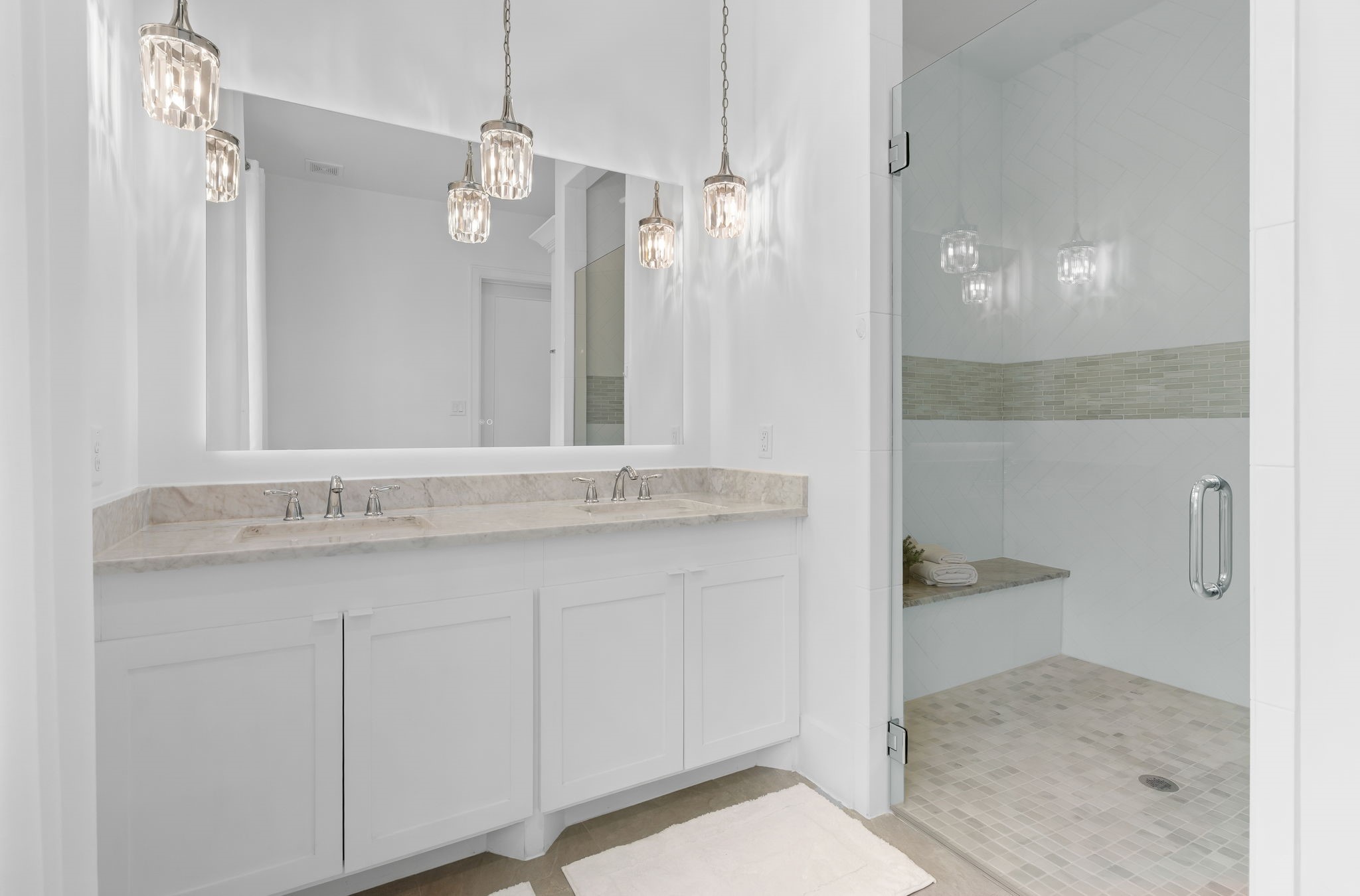 10 Riata Drive Magnolia, TX 77354 - Photo 28 of 48 Downstairs primary bath has marble counters, custom cabinetry, dual vanity, chrome fixtures, updated lighting and is handicapped ready with a large walk-in/roll-in shower.