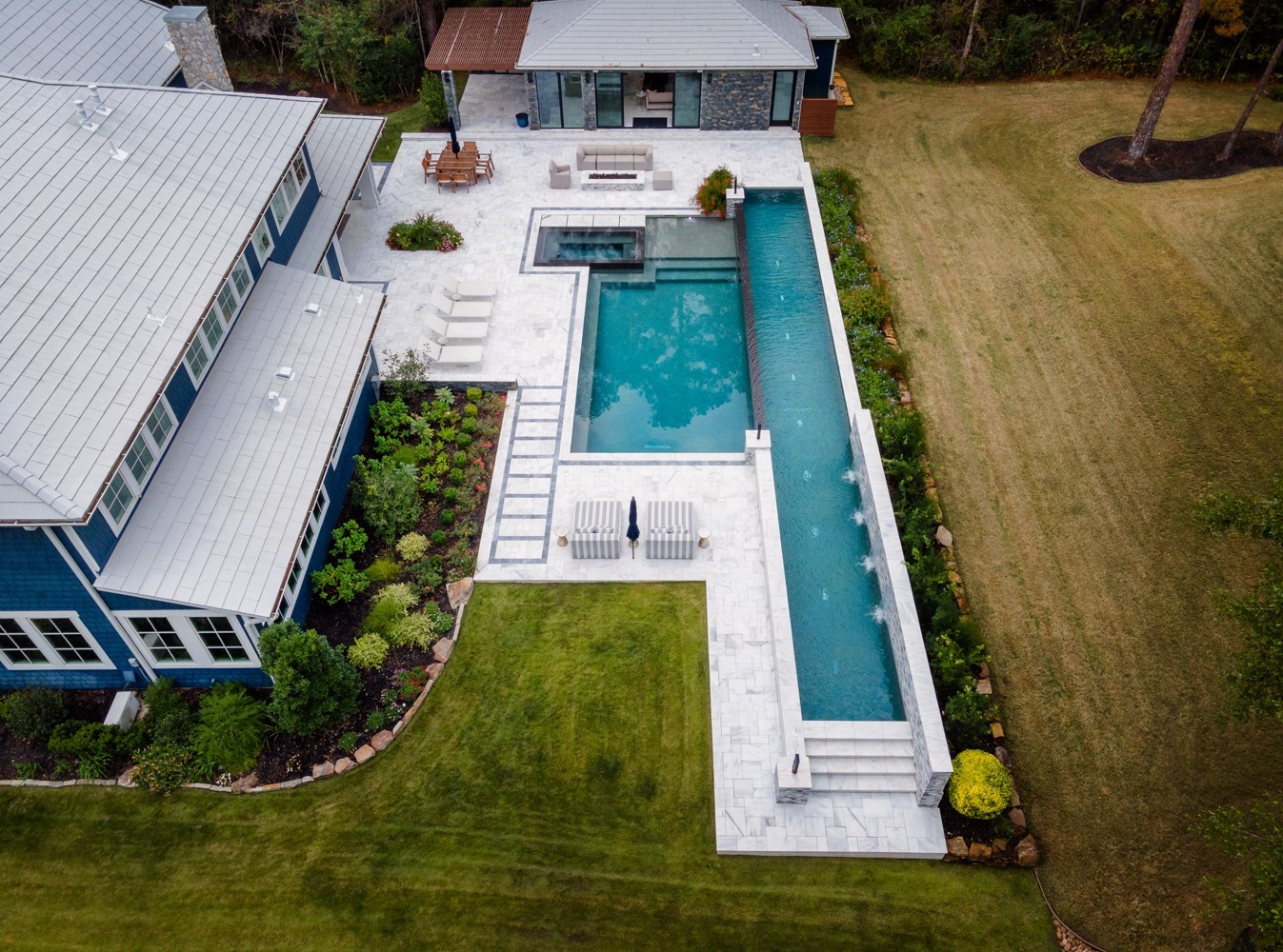 10 Riata Drive Magnolia, TX 77354 - Photo 5 of 48 Aerial view of this magnificent outdoor oasis including an air conditioned guest/pool house, 8' x 4' linear fire pit 5+ poolside seating areas, including covered back patio with double-sided fireplace, and large marble pool deck and outdoor speakers.