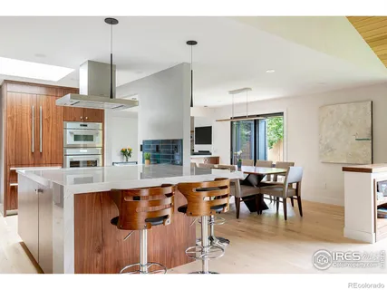 a dining hall with stainless steel appliances kitchen island granite countertop a dining table chairs and a refrigerator