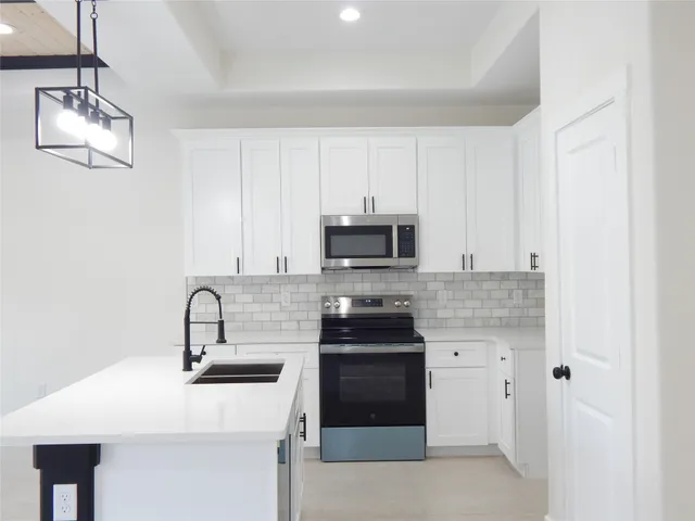 a kitchen with stainless steel appliances a stove a sink and white cabinets