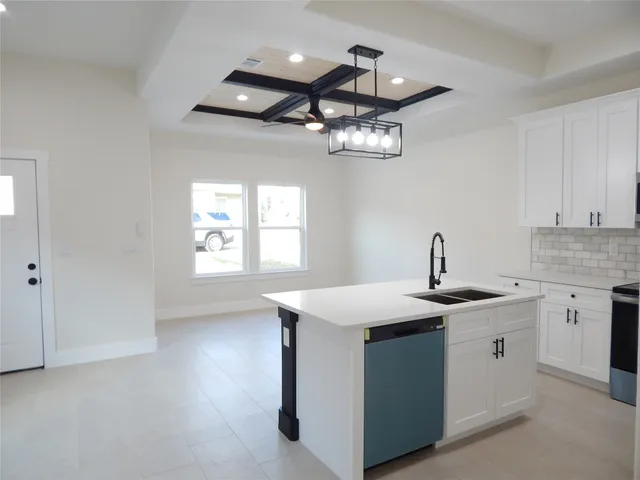 a kitchen with stainless steel appliances granite countertop a sink dishwasher a stove and white cabinets with wooden floor