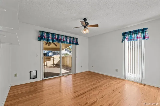a view of empty room with wooden floor and ceiling fan