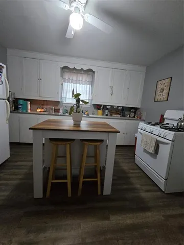 a kitchen with sink a stove and chairs with wooden floor