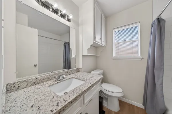 a bathroom with a granite countertop sink a toilet and a mirror