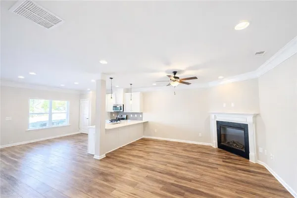 a view of a kitchen with a stove cabinets a ceiling fan and wooden floor