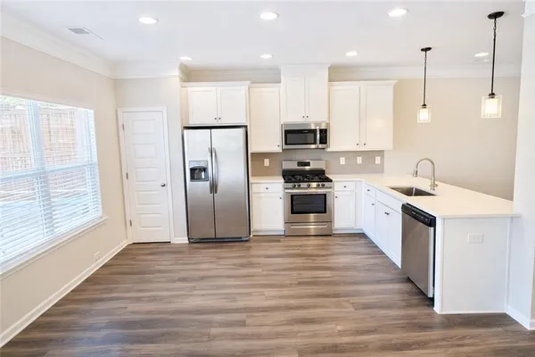 a large kitchen with stainless steel appliances kitchen island a large counter top and wooden floors