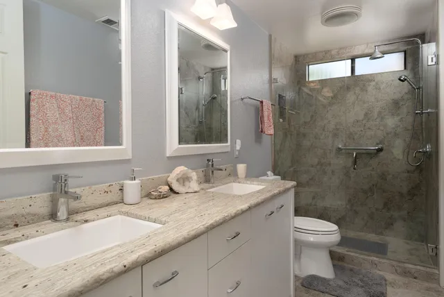 a bathroom with a granite countertop sink a toilet and a mirror