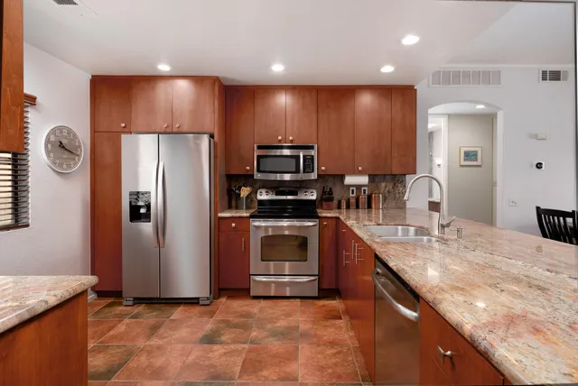 a kitchen with stainless steel appliances granite countertop a refrigerator a sink and a stove