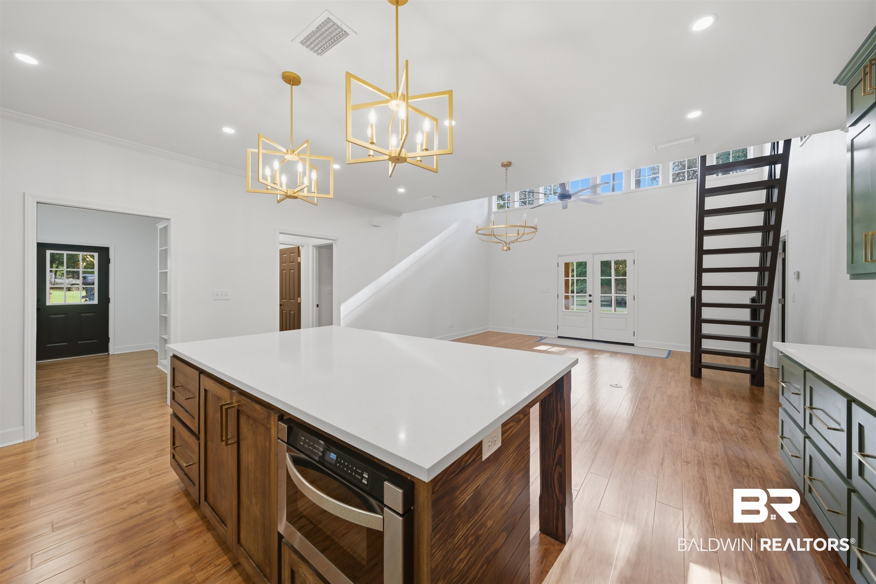 14128 Jackson Lane Foley, AL 36535 - Photo 15 of 36 Spacious open-concept interior featuring wood-finish flooring, a kitchen island with a light-toned countertop, and dual brass chandeliers