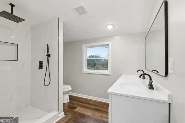 a bathroom with a granite countertop sink a toilet and shower