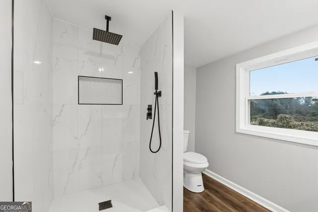 a bathroom with a granite countertop shower a toilet and a sink