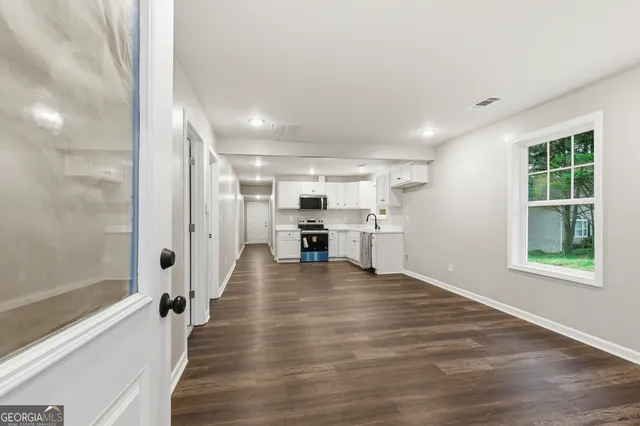a view of an empty room with wooden floor and a window