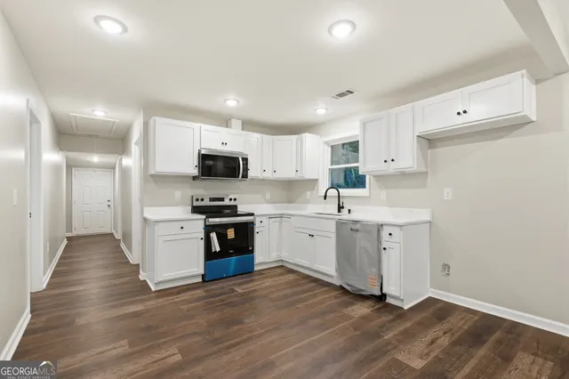 a kitchen with granite countertop white cabinets and stainless steel appliances