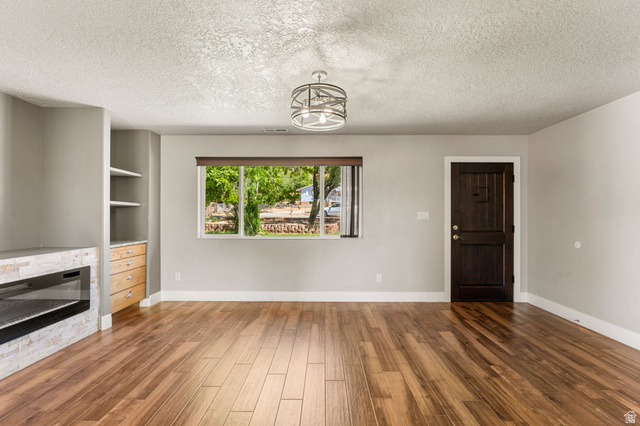 55 Spring Drive Toquerville, UT 84774 - Photo 6 of 36 Unfurnished living room featuring a fireplace, a textured ceiling, and dark wood-style floors