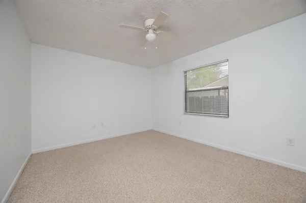 an empty room with a window and a ceiling fan