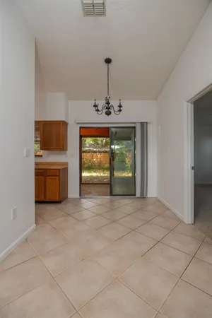 a view of an empty room with a window and kitchen view