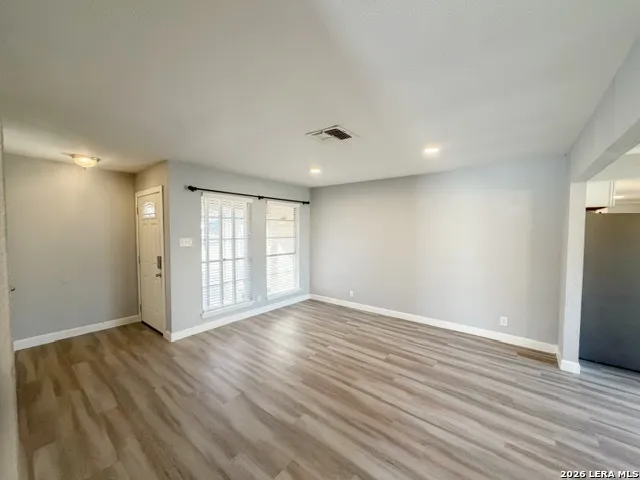 a view of an empty room with wooden floor and a window