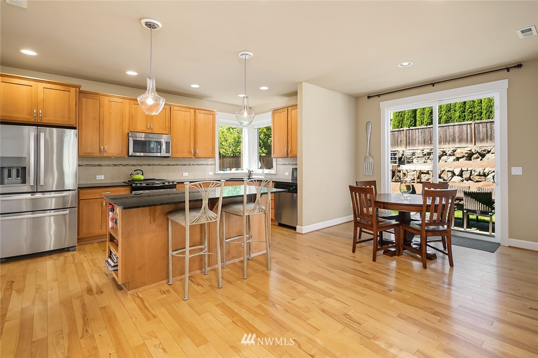 6308 Southeast 2nd Street Renton, WA 98059 - Photo 6 of 29 a kitchen with stainless steel appliances granite countertop a stove top oven a sink dishwasher a dining table and chairs with wooden floor