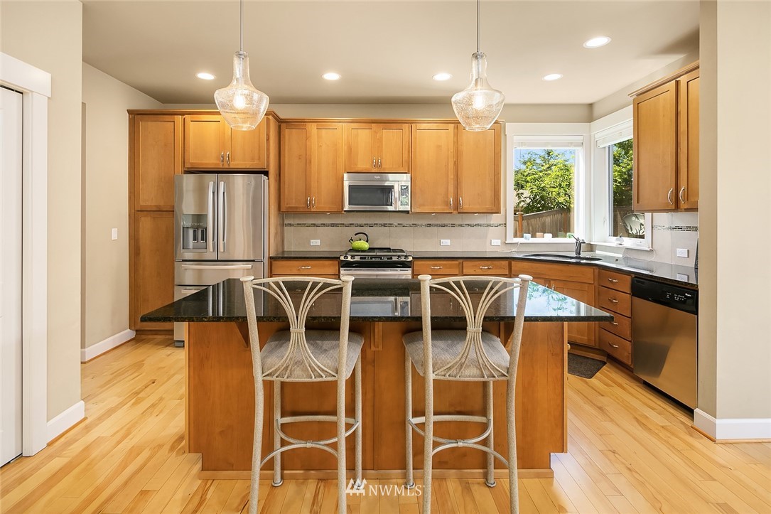 6308 Southeast 2nd Street Renton, WA 98059 - Photo 7 of 29 a kitchen with stainless steel appliances granite countertop a stove top oven a sink dishwasher a dining table and chairs with wooden floor