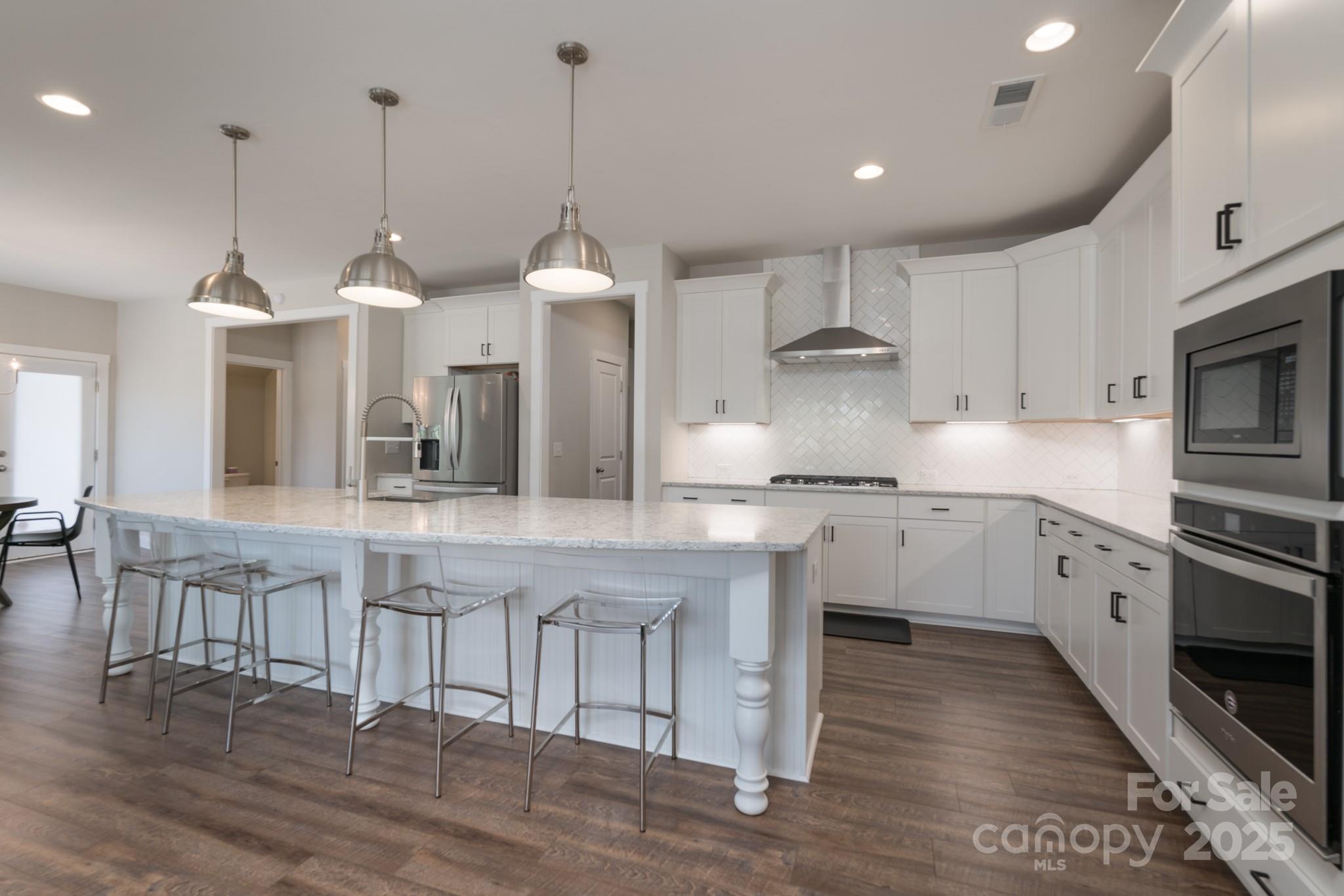 1180 Weir Court Fort Mill, SC 29708 - Photo 12 of 37 a kitchen with kitchen island granite countertop a stove a sink a dining table and chairs with wooden floor