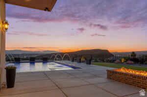 1141 East Lost Ridge Drive Washington, UT 84780 - Photo 17 of 108 Expansive patio featuring a rectangular swimming pool with water features, a built-in brick fire pit, and a mountain backdrop