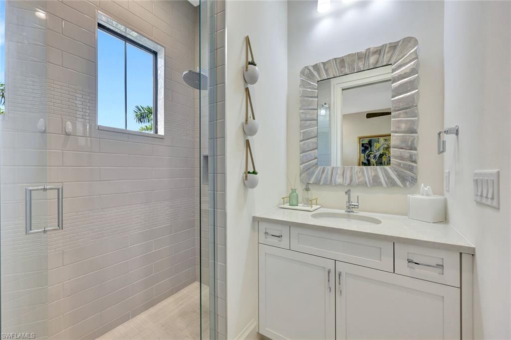 16350 Corsica Way, Unit 202 Naples, FL 34110 - Photo 24 of 39 a bathroom with a granite countertop sink a mirror and a shower