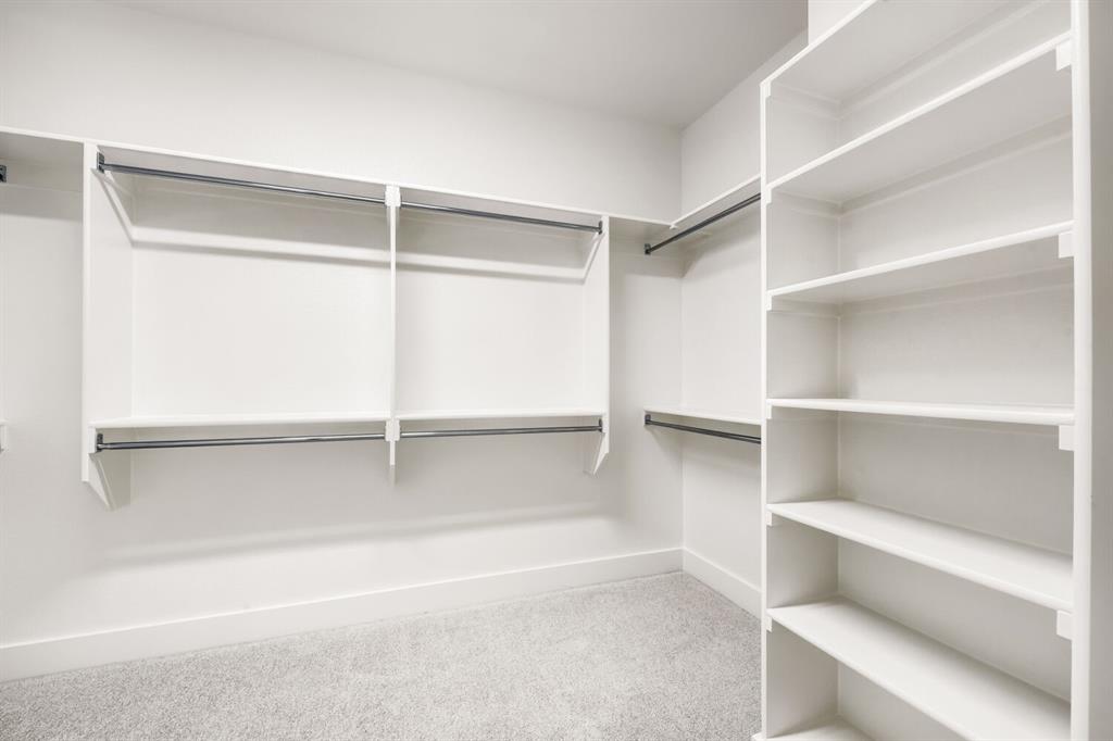 733 Red Cedar Road Haslet, TX 76052 - Photo 20 of 28 Walk-in closet featuring white built-in shelving, multiple hanging rods, and light gray carpet