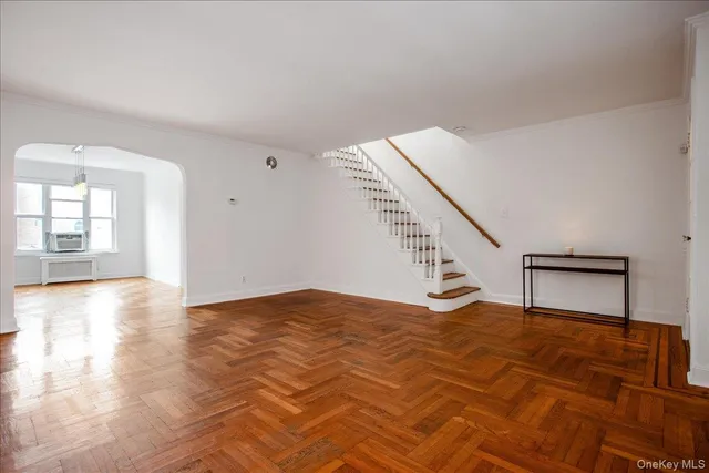 a view of an empty room with wooden floor and stairs