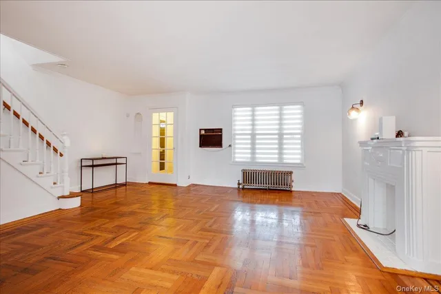 a view of an empty room with window and wooden floor