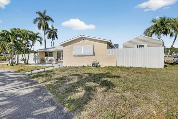 a view of a house with a yard and palm trees