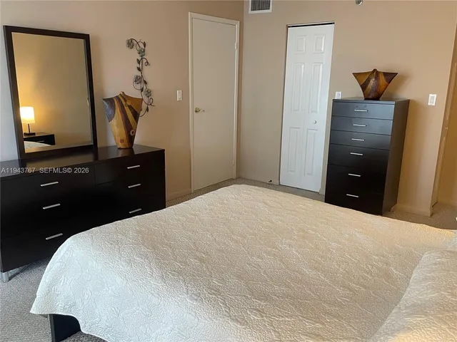 a bedroom with a bed and lamp on dresser