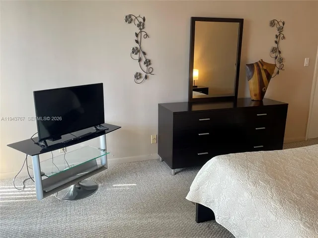 a bedroom with a bed and lamp on dresser