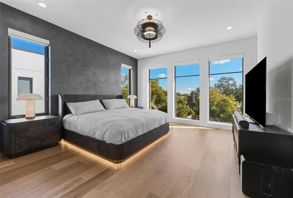 a spacious bedroom with a large bed and a flat tv screen on dresser