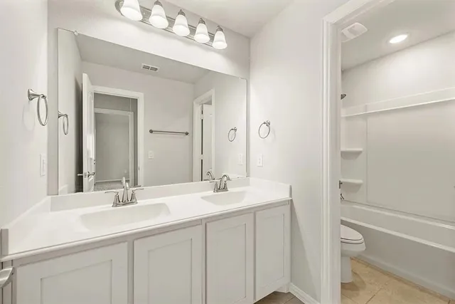 a bathroom with a double vanity sink mirror and a bathtub