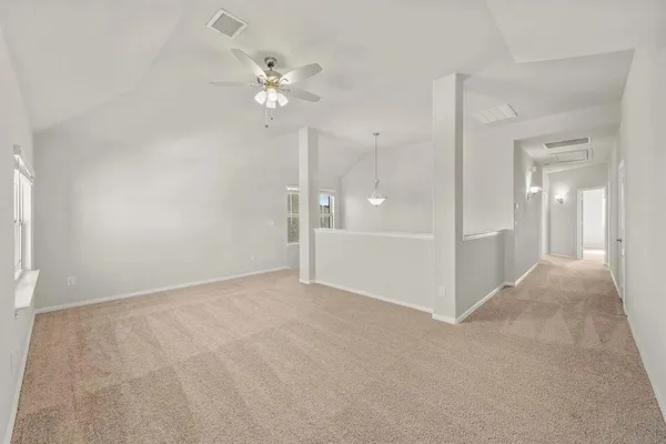 a view of an empty room with a chandelier fan