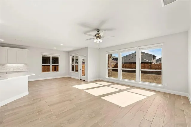 a view of an empty room with a window and a kitchen