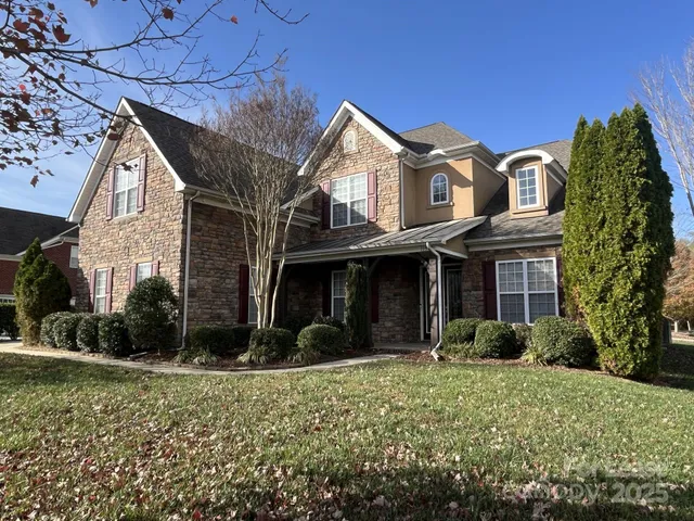 a view of a brick house with a yard and plants