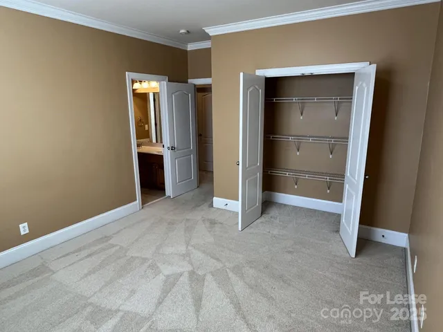 a view of an empty room with closet and a window