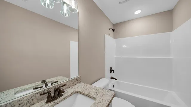a bathroom with a granite countertop sink a toilet and shower