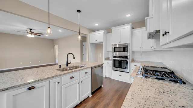 a kitchen with stainless steel appliances granite countertop a sink stove and cabinets