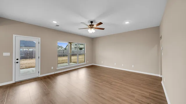 a view of an empty room with a window and wooden floor