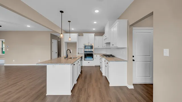 a kitchen with stainless steel appliances a refrigerator a sink dishwasher and a stove with wooden floor