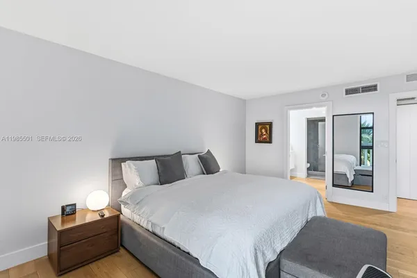 a spacious bedroom with a bed and wooden floor